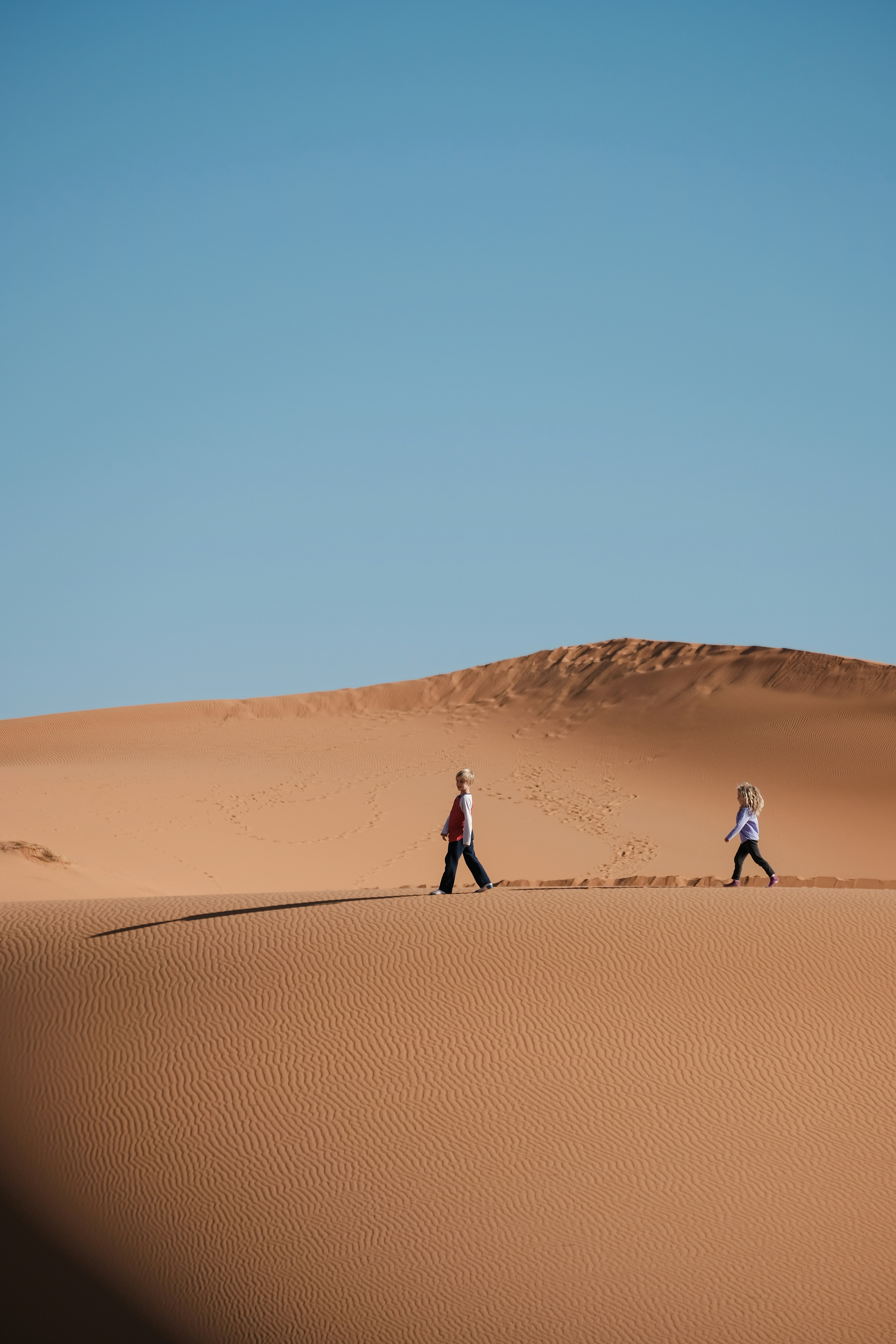 man and woman walking on brown sands